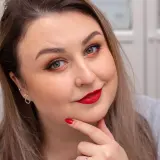 Kobieta z wyrazistym makijażem na święta: czerwone usta, złote cienie do powiek i czarna kreska.