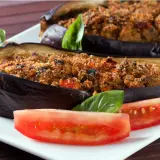 Melanzane ripiene al forno velocissime, dorate e gustose, servite con pomodoro fresco e basilico.
