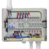 Wnętrze skrzynki elektrycznej z wyłącznikiem głównym 32A i kilkoma mniejszymi zabezpieczeniami nadprądowymi, okablowanie L, N, PE.