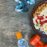 Zdrowa owsianka z owocami, migdałami, wodą i hantlami. Czy białko pomaga schudnąć? To śniadanie to dobry początek!