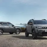 Dwa nowe SUV-y Dacia Duster, idealne na wyprawy do 40 tys. zł, stoją na kamienistym podłożu w górskim krajobrazie.