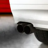 Dwa końcówki wydechu samochodu z wydobywającą się z nich chmurą dymu.