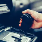 Dłoń trzymająca dźwignię zmiany biegów w samochodzie. Pytanie: czy mając prawo jazdy na automat można jeździć manualem?