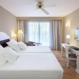 Habitación doble con camas blancas y escritorio en el hotel Occidental Isla Cristina.
