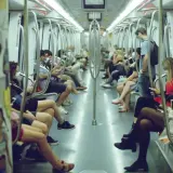 Interno di un vagone della metro di Roma, con passeggeri seduti e in piedi. Si vede come funziona la metro a Roma, con le barre di sostegno e i sedili bianchi.