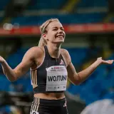 Uśmiechnięta Klaudia Wojtunik z rozłożonymi rękami na stadionie, celebrująca sukces.