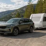 Grön Skoda Kodiaq drar en husvagn vid en sjö i Sverige. Perfekt för ett skoda kodiaq test i naturen.