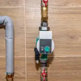 Nowoczesna pompa cyrkulacyjna a obiegowa z cyfrowym wyświetlaczem, podłączona do instalacji grzewczej.