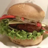 Pyszny burger z Krowarzywa Kraków: soczysty kotlet roślinny, świeża sałata, ser, pomidor i kiełki w miękkiej bułce.