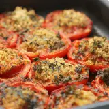 Tomates au barbecue, coupées en deux et garnies d'une chapelure aux herbes, cuites dans un plat.
