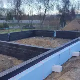 Budowa domu w toku. Widać zbrojenie i izolację fundamentów.