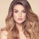 Frau mit vollem, welligem Haar und Sommersprossen. Sie träumt davon, dickere Haare zu bekommen, um diesen Look zu erzielen.