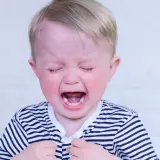 Un bimbo di 2 anni piange disperato, un classico dei capricci. Le guance rosse e la bocca spalancata mostrano tutta la sua frustrazione.