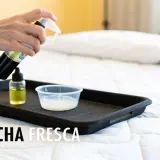 Mano rociando limpiador sobre una bandeja con líquidos, parte de un tutorial sobre como limpiar un colchon.