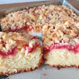 Puszysta babka z truskawkami i kruszonką, pokrojona na dwa kawałki, prezentuje się apetycznie.