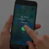 Palec dotyka ikony połączenia alarmowego na ekranie telefonu, pokazując, jak odblokować telefon przez połączenie alarmowe w sytuacji awaryjnej.