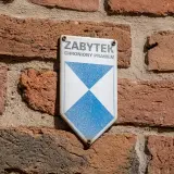 Tabliczka "Zabytek chroniony prawem" na ceglanej ścianie. Może być potrzebna do wypełnienia wzoru wniosku o wykreślenie z gminnej ewidencji zabytków.