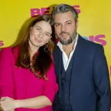 Karolina Malinowska Janiak i jej partner pozują na tle żółtej ścianki z napisem "BEJBIS".