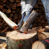 Mann spaltet Holz mit Axt. Mit der richtigen Technik kann man den Holzspalter schneller machen und effizienter arbeiten.