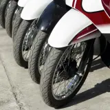 Rzędy motocykli gotowe do dpd transportu. Widoczne koła, opony i błotniki w kolorach białym, czarnym i czerwonym.