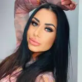 Stella z Love Island, z długimi czarnymi włosami i wyrazistym makijażem, pozuje do zdjęcia.