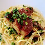 Un morceau d'échine de porc croustillante sur des pâtes crémeuses, garni de ciboule fraîche. Un délice !