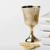 Złoty kielich, stos białych ksiąg z napisem "HOLY BIBLE", różaniec i opłatki. Symbolika sakramentu, który może być odnotowany w akcie chrztu.