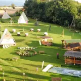 Wioska indiańska w Lubelskiem z tipi, drewnianymi chatkami i miejscem na ognisko.