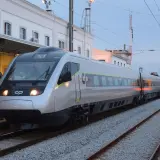 Tren moderno plateado y otro amarillo en estación, listos para el viaje de Lisboa a Oporto.