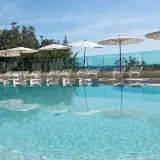 Piscina con lettini e ombrelloni, riflessi sull'acqua cristallina. Un angolo di relax a **Abbadia San Salvatore terme**.