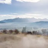 Kamper na polu namiotowym z widokiem na góry. Mgła otula dolinę, tworząc magiczną atmosferę.