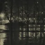 Nocny park, mokre alejki odbijające światła latarni i okien. Piktorializm w fotografii oddaje nastrój i atmosferę.