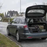 Mörkgrå Kia Ceed kombi med öppen baklucka, packad med barnvagn och väskor. Perfekt för en familjeresa, som i ett kia ceed sw test.