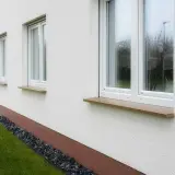 Eleganckie parapety kamienne w ciepłych kolorach dodają uroku białej elewacji.