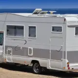 Camping-car blanc stationné sur une aire de camping-car à Bormes-les-Mimosas, face à la mer Méditerranée.