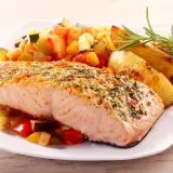 Pieczony łosoś z ziołami i czosnkiem, podany z pieczonymi ziemniakami i warzywami. Idealne przyprawy do ryby z piekarnika, które podkreślają jej delikatny smak.