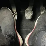 Pies con zapatillas negras listas para arrancar. Hay que pisar el embrague para arrancar el coche.