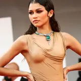 Zendaya med vattenkammat hår, klädd i en beige klänning och en grön ormhalsband.