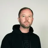 Daniel Holmgren, en man med blå ögon och skägg, bär en svart huvtröja.