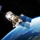 Satelita z dużymi panelami słonecznymi krąży nad Ziemią. Widać jego skomplikowaną konstrukcję i antenę.