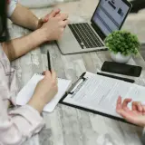Rozmowa o tym, jak zrezygnować z OC. Na stole dokumenty, laptop i telefon.