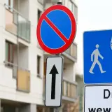 Znak zakaz postoju informuje, że nie można tu parkować. Obok znak drogi wewnętrznej z ikonami pieszych i samochodu.