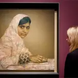 A striking **Malala Yousafzai portrait** shows her looking thoughtfully, her hands resting on a book. A woman observes the artwork.