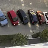 Szary samochód, czerwony, czarny, granatowy, rudy, biały, ciemnogranatowy i srebrny stoją na parkingu. Może to być inspiracja do wypełnienia wniosku o miejsce parkingowe wzór.