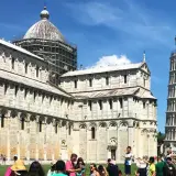 Turyści podziwiają, gdzie jest krzywa wieża w Pizie, obok katedry i baptysterium na Piazza dei Miracoli.