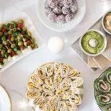 Kolorowe, zdrowe przekąski na imprezę: szaszłyczki caprese, tortille z kurczakiem i kukurydzą, roladki ze szpinakiem i łososiem, hummus i guacamole.