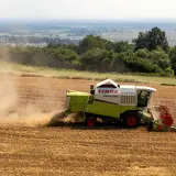 Kombajn zbożowy CLAAS Mega 350 zbiera plony na polu. Dymiące maszyny rolnicze to symbol ciężkiej pracy, która dzięki płatnościom bezpośrednim staje się bardziej opłacalna.