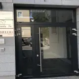 Wejście do budynku z tabliczkami informacyjnymi, w tym "SKORECKI KANCELARIA DORADCY FINANSOWEGO".