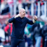 Nowy trener Widzewa, z zaciśniętymi pięściami, krzyczy z radości na tle trybun.