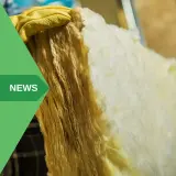 Mano con guanto giallo tiene isolante. Attenzione: la lana di vetro fa male se non maneggiata con cura.